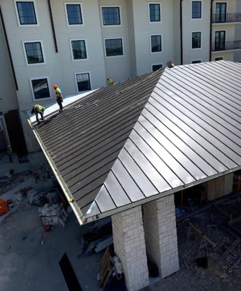 Crew installing standing seam metal roof panels on a commercial project in Boston